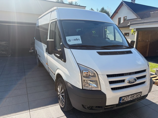 Biały Ford Transit z kartką Veln za przednią szybą
